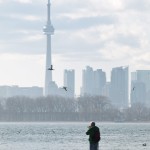 Photographer on Jetty Against Toronto Skyline